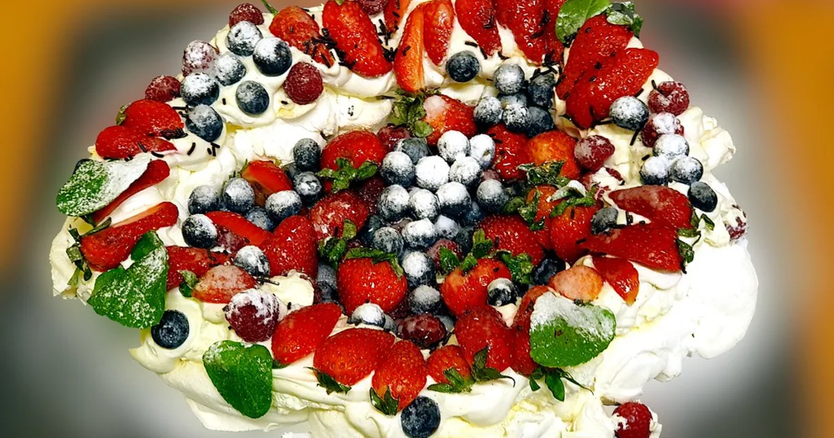 Pavlova topped with fruit and cream